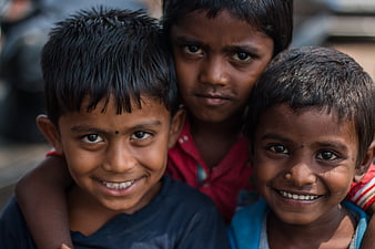 Close-up portrait of three smiling Indian children outdoors