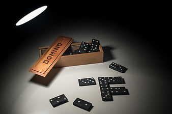 Black dominoes in wooden box with dramatic lighting