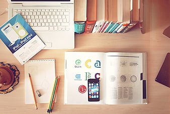 Flat lay of design workspace with laptop, books, and smartphone