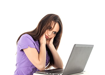 Bored young woman resting chin on hands looking at laptop