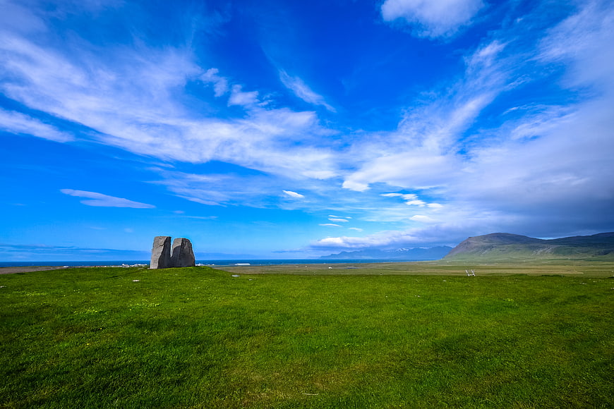 Vibrant Green Landscape with Stone Monolith and Blue Sky