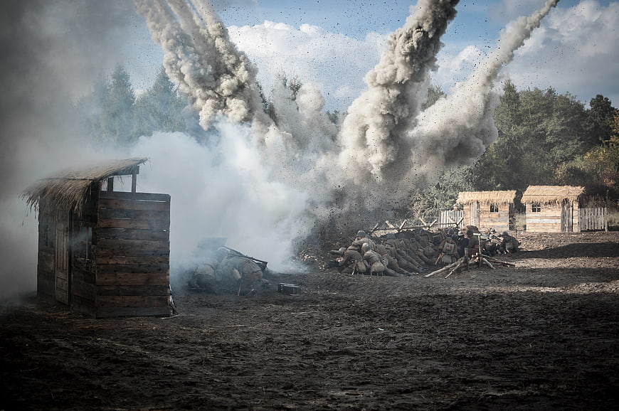 Dramatic war reenactment with explosions and soldiers in trenches