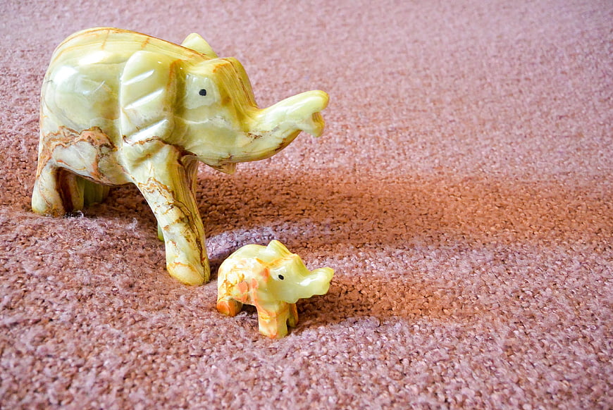 Carved Onyx Elephant Figurines on Textured Pink Surface