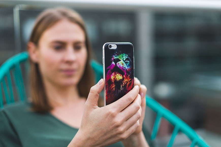Woman holding smartphone with colorful lion wallpaper