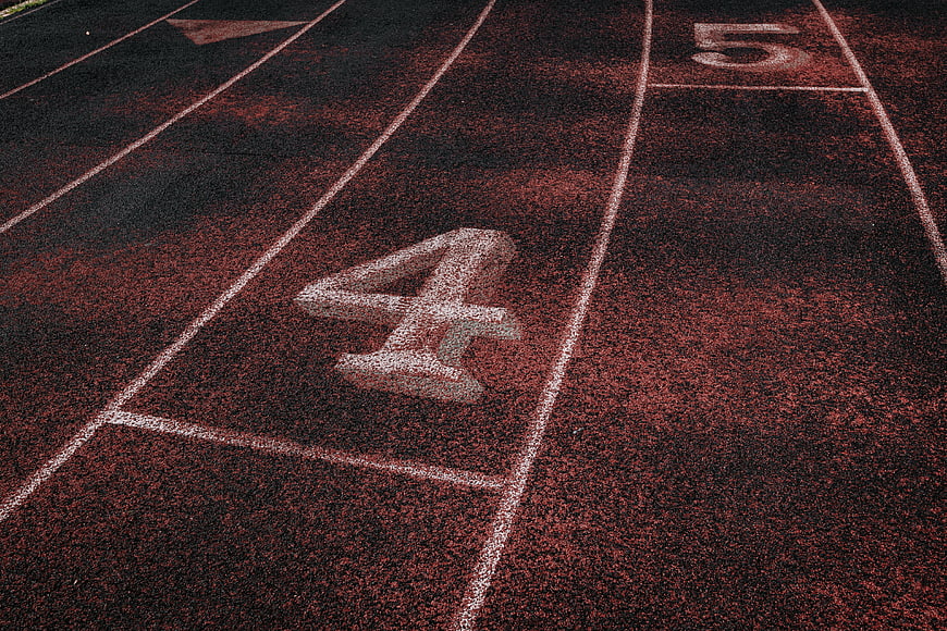 Close-up of red running track lanes with white numbers
