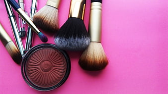 Flat lay of makeup brushes and blush on pink background