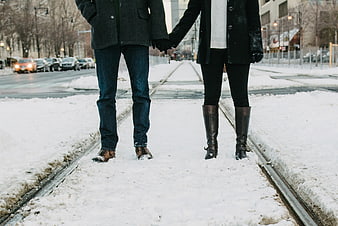 Couple Holding Hands Walking on Snowy Train Tracks