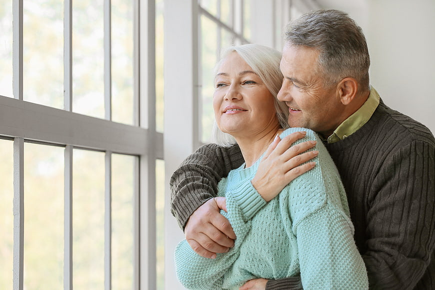 Senior couple embracing affectionately by a bright window