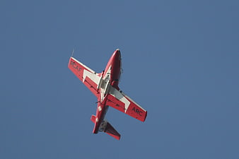 Red and White Snowbird Jet Flying Against Blue Sky