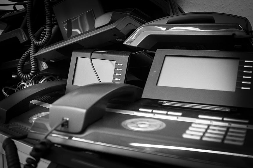 Stack of discarded office telephones and electronic waste