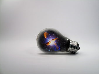 Light bulb containing a colorful galaxy and stars on a white background