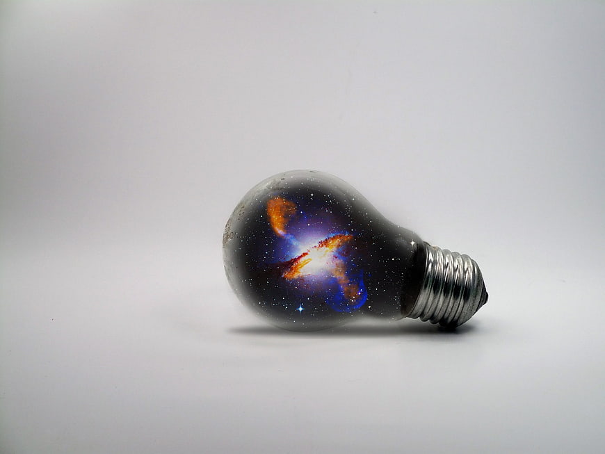 Light bulb containing a colorful galaxy and stars on a white background