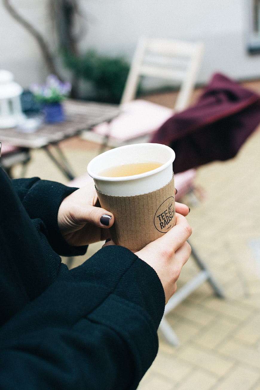 Hands holding takeaway tea cup outdoors