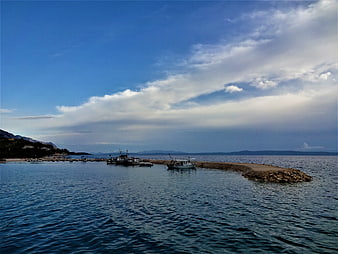 Fishing boats docked at a stone pier in a calm blue sea
