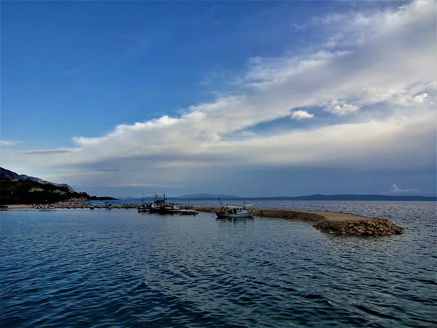 Fishing boats docked at a stone pier in a calm blue sea