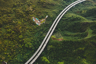 Aerial view of highway bridge winding through lush green mountains