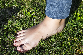 Barefoot woman walking on green grass in sunlight