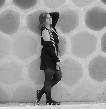 Young woman in black outfit posing against textured concrete wall