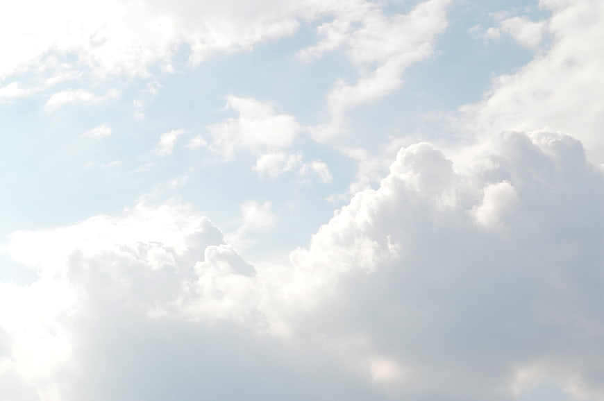 Fluffy white cumulus clouds against a bright blue sky