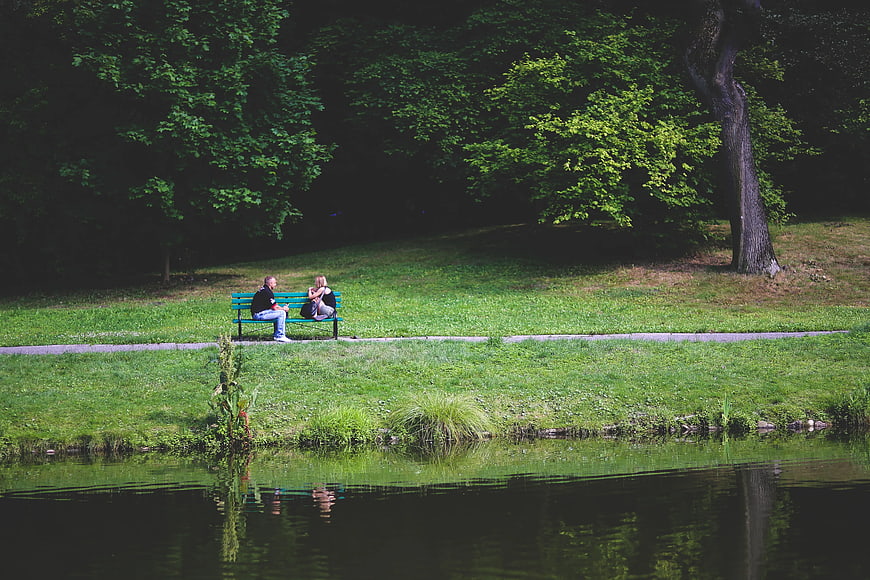 Couple sitting on park bench by lake