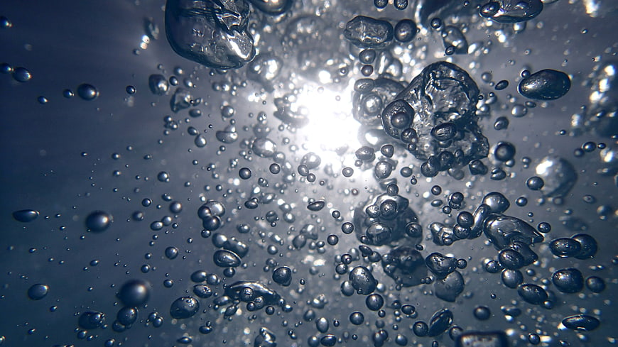 Underwater macro shot of rising air bubbles with bright backlight