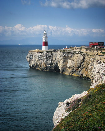 Lighthouse on Rocky Cliff Overlooking Blue Ocean