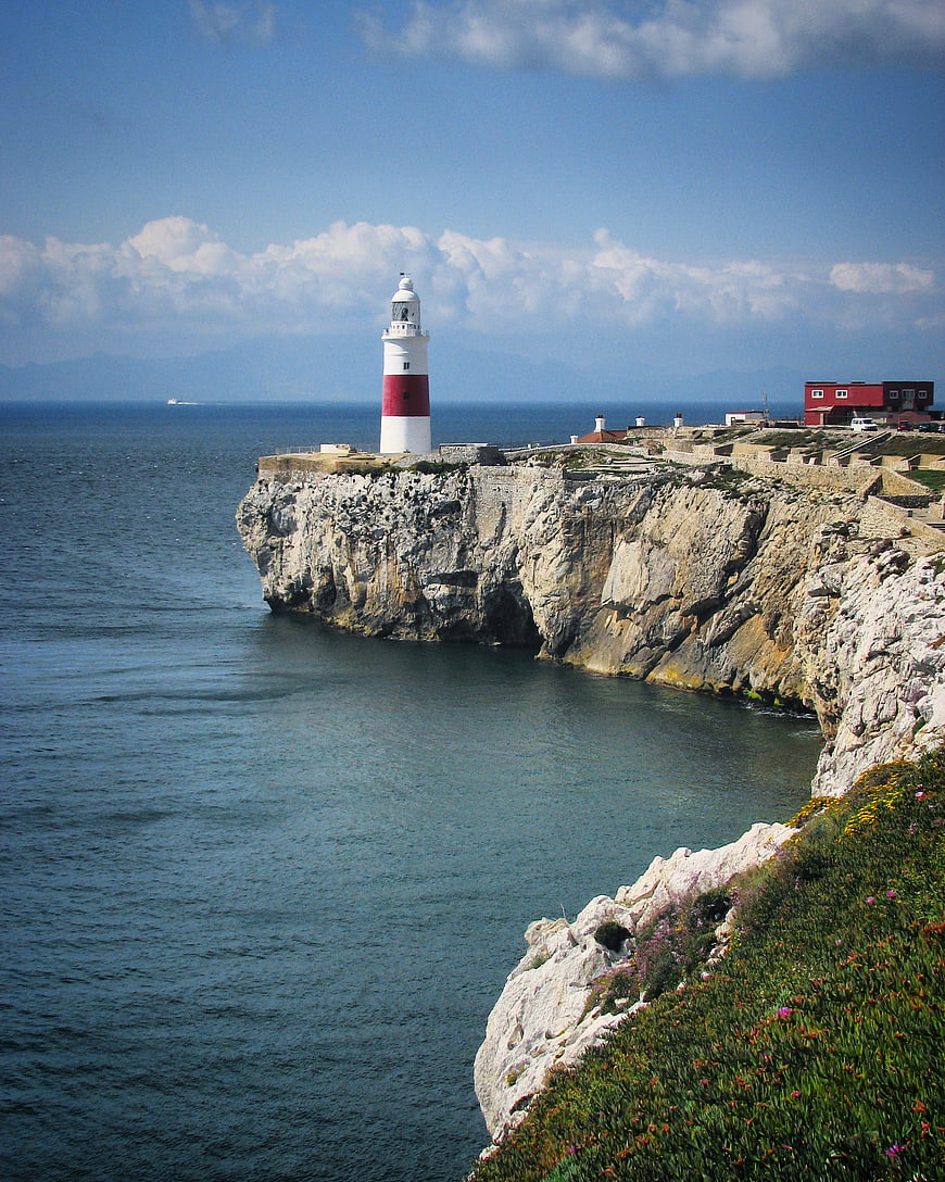 Lighthouse on Rocky Cliff Overlooking Blue Ocean