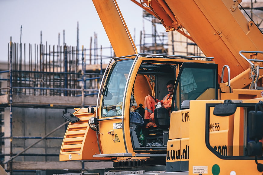 Construction worker operating yellow crane at building site