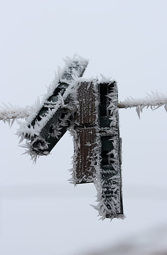 Frost-covered clothespin on a frozen clothesline in winter