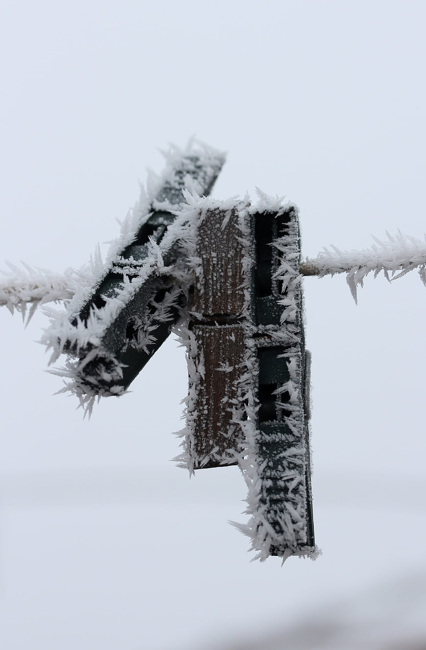 Frost-covered clothespin on a frozen clothesline in winter