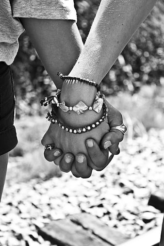 Close-up of two people holding hands with bracelets outdoors