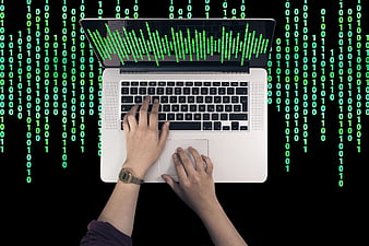 Hands typing on laptop with green binary code background