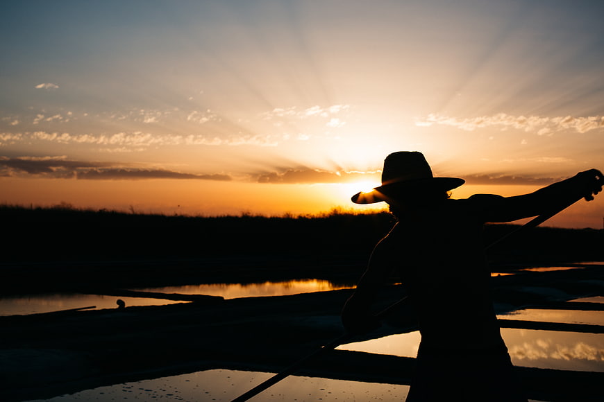 Silhouette of Man in Hat Rowing Boat at Sunset