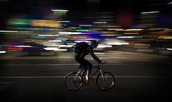 Night courier cycling through city with motion blur