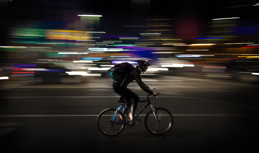 Night courier cycling through city with motion blur