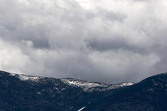 Dramatic Snow-Capped Mountains Under Stormy Clouds
