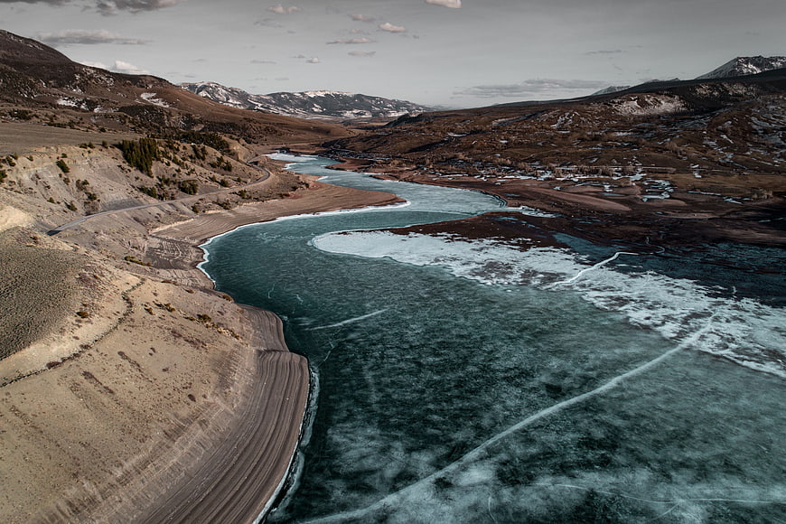 Aerial view of winding frozen river in winter mountain landscape