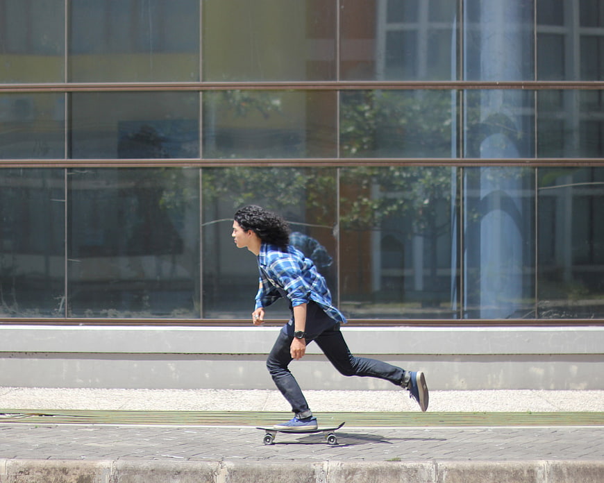 Young man skateboarding on city sidewalk