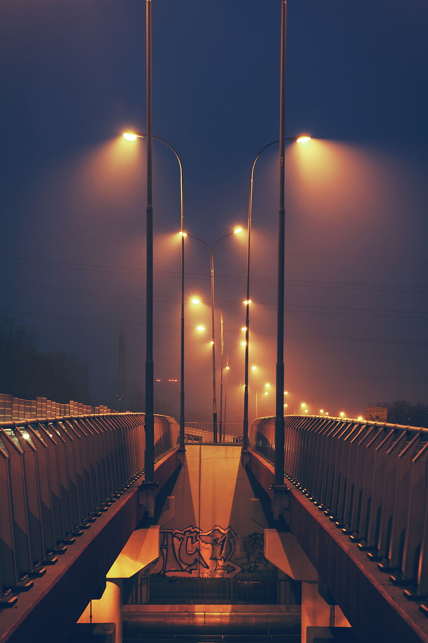 Foggy urban bridge with glowing streetlights at night