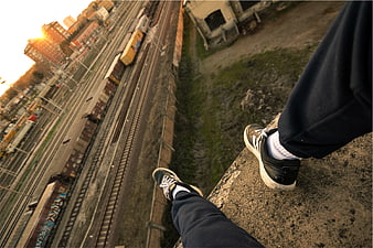 First-person view of sneakers on edge overlooking train tracks