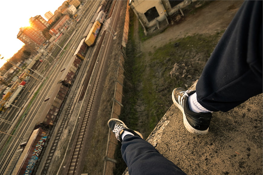First-person view of sneakers on edge overlooking train tracks