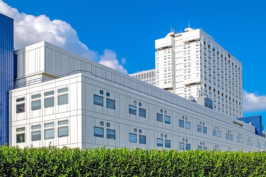 Modern white hospital building with blue sky and green hedge