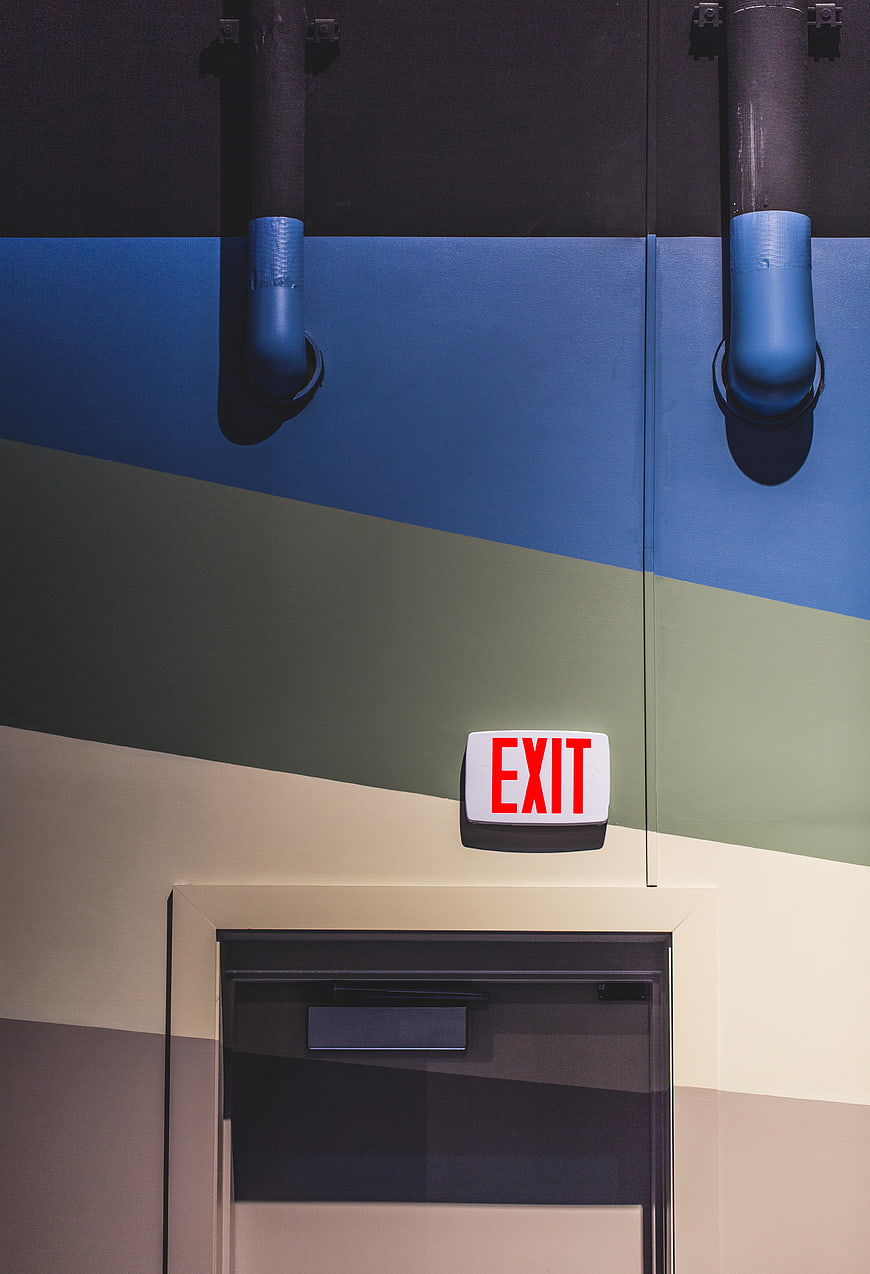 Colorful striped wall with exit sign and pipes