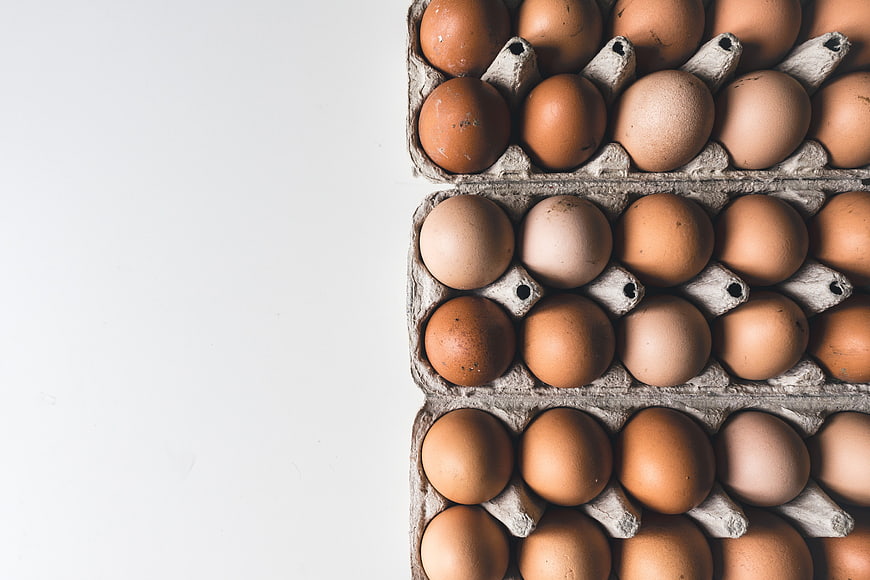 Top View of Brown Eggs in Cardboard Cartons on White Background