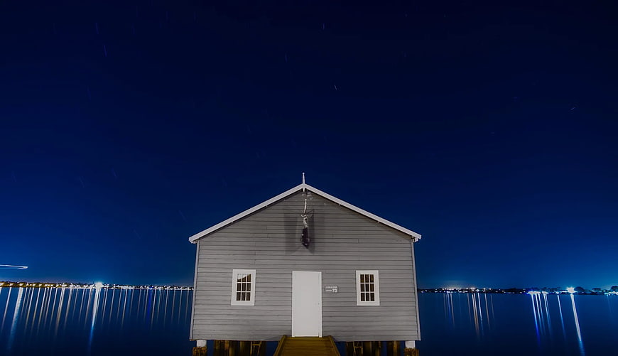 Gray Wooden House on Stilts by Water at Night