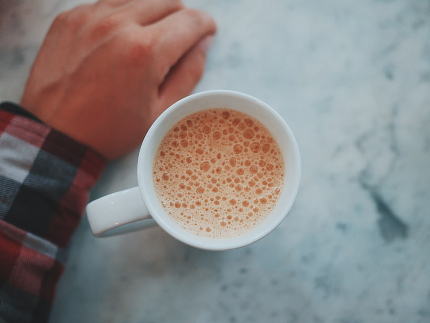 Top View of Coffee Cup with Hand on Marble Table