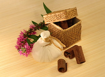 Woven basket with cinnamon sticks, herbal pouch, and pink flowers