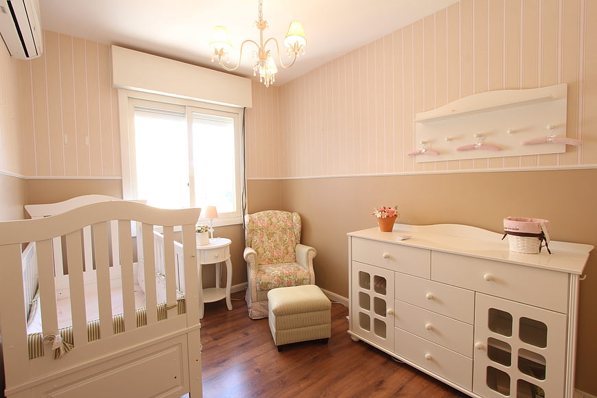 Bright nursery with white crib, dresser, and floral armchair