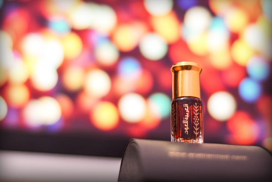 Luxury perfume bottle with gold cap against colorful bokeh background
