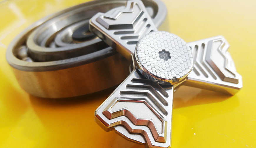 Metal fidget spinner and bearing on yellow background